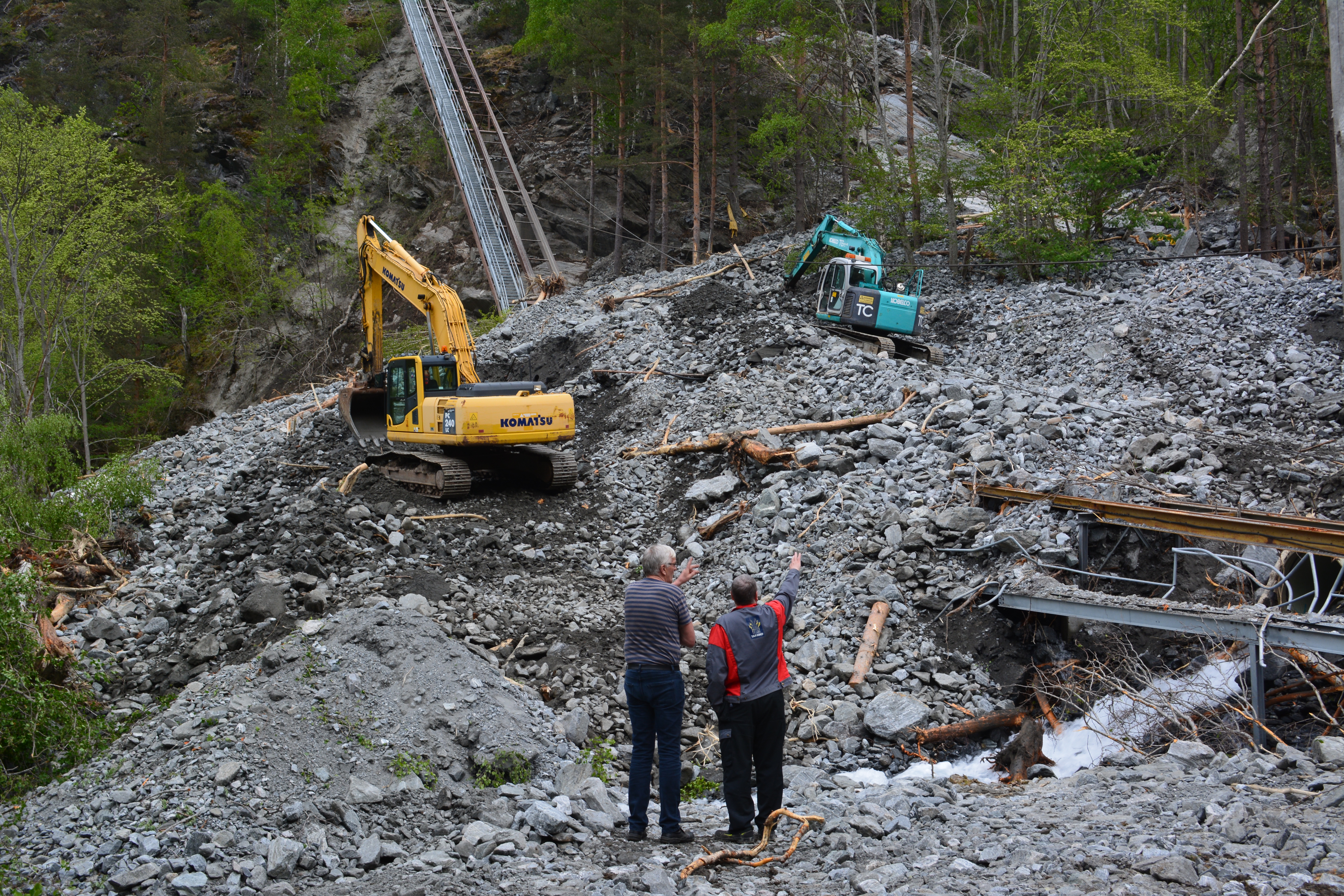 Nærbilde av gravemaskinskuffe som graver i sand og jord.